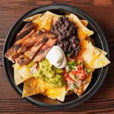 Nacho supreme — tortilla chips under melted cheese, beans, guacamole and pico